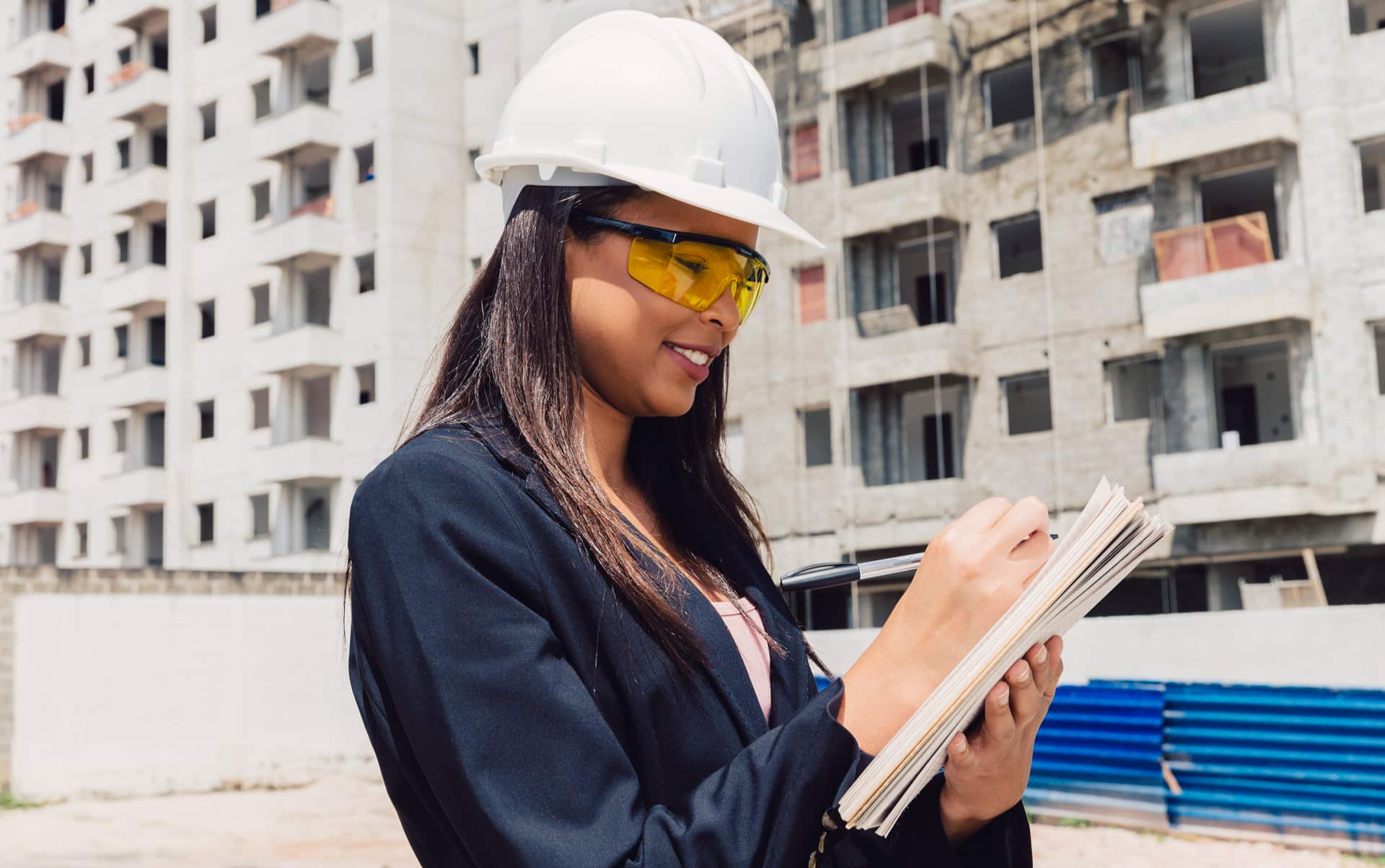 african american lady safety helmet with notepad near building construction